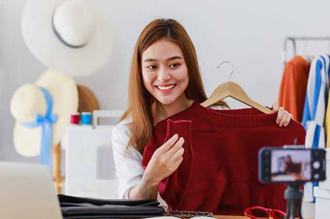 Mujer Sonriente Mostrando Prenda de Ropa en la Cmara de su Telfono